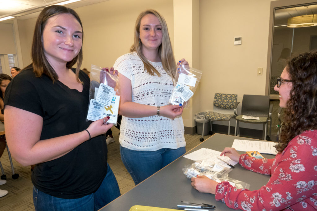 Sage Nursing students hold kits containing naloxone and caregiver protection tools.
