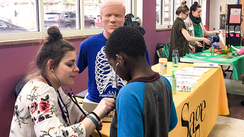 A Russell Sage College Nursing student demonstrates a stethoscope during an activity fair at the Boys & Girls Clubs of the Capital Area in Troy.