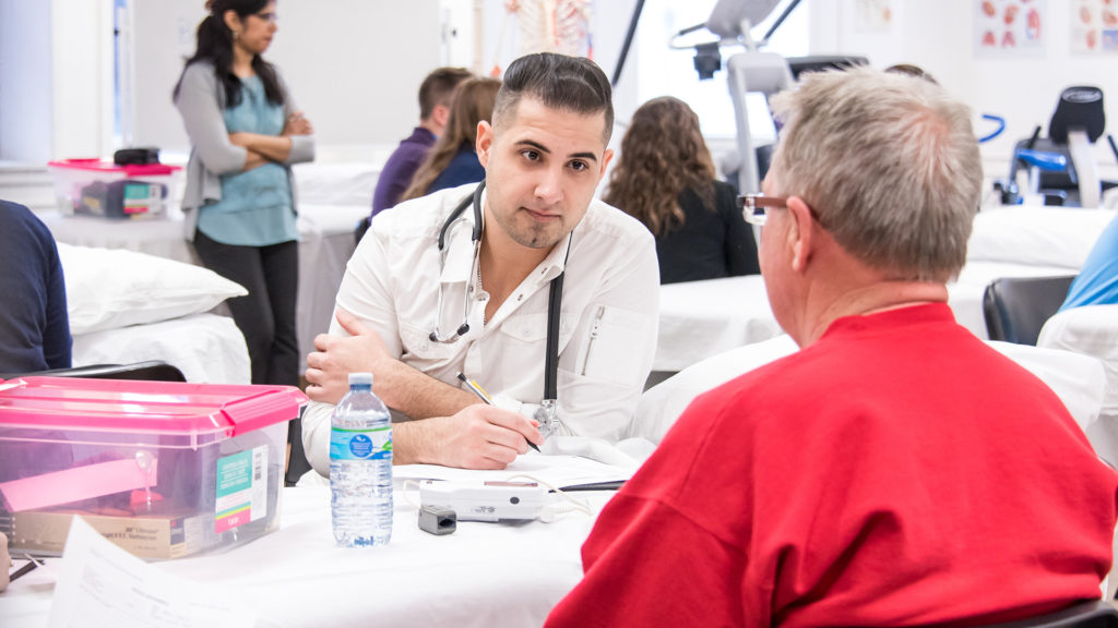DPT candidate consults with community member under faculty supervision at clinic sponsored by DPT program.