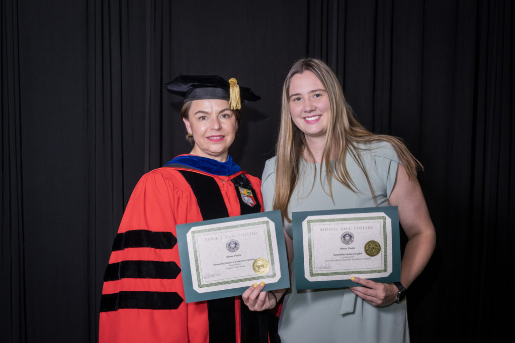 woman in red graduation gown and black hat standing with a female college student with long blond hair holding two certificates