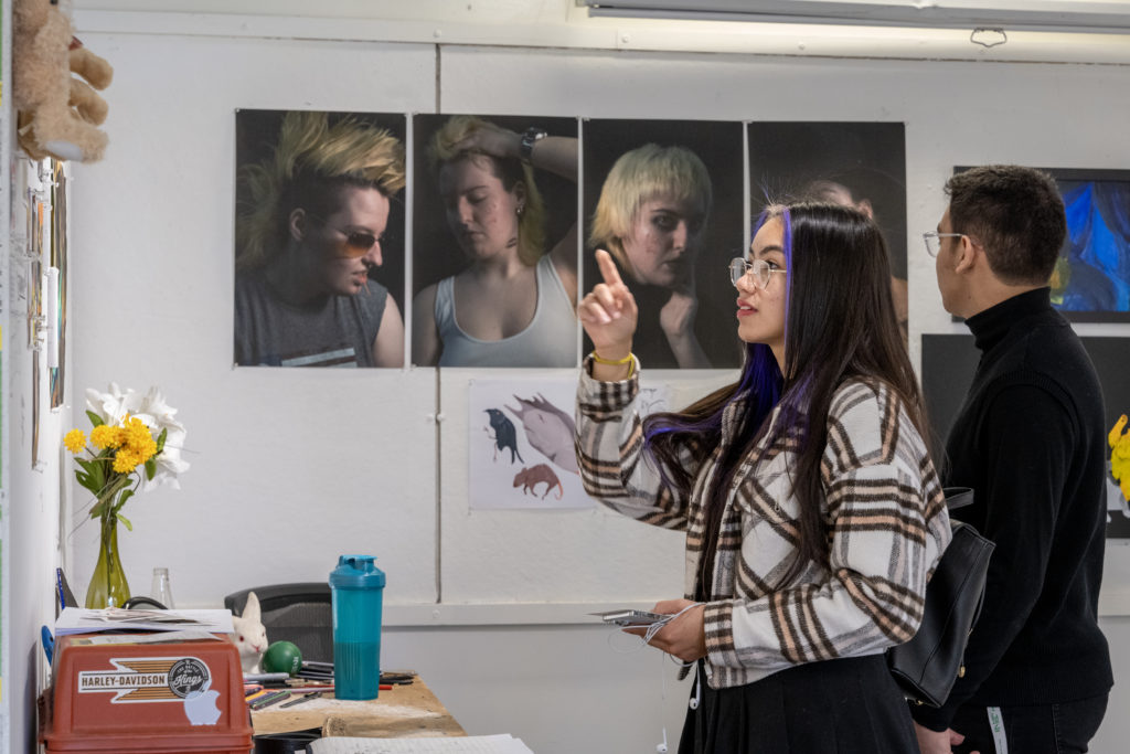 Student gestures toward work in art gallery