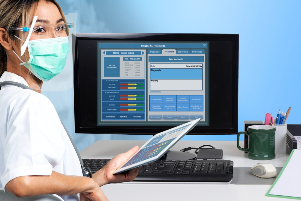 Nurse in a mask reviewing charts on a computer. 