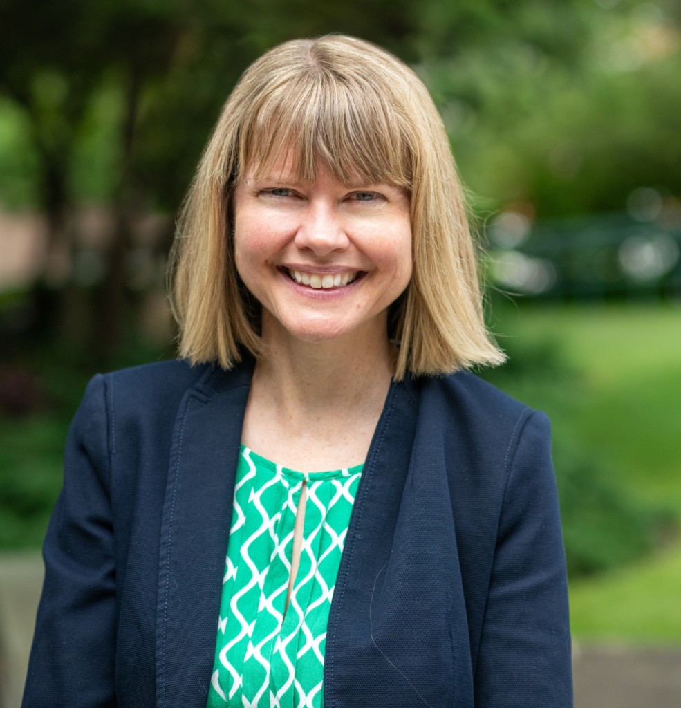 person in business suit smiling at camera outside