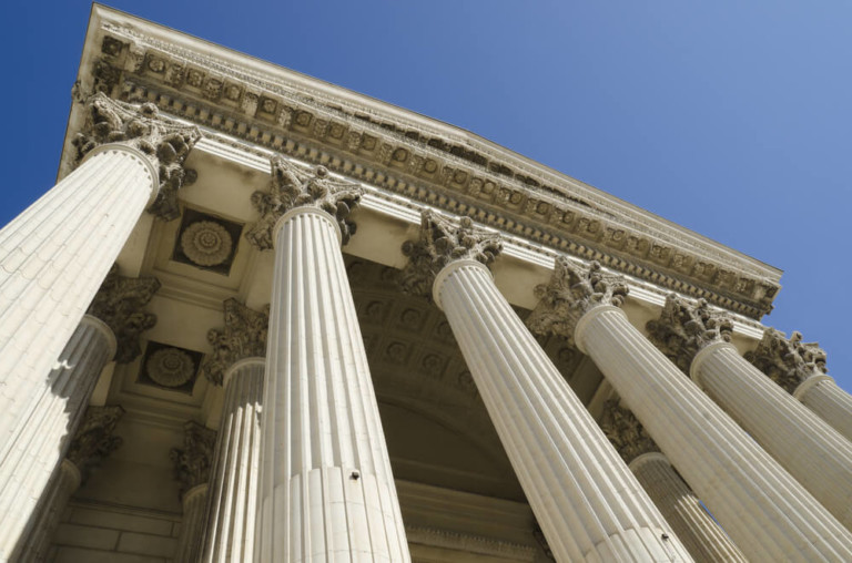 exterior of a courthouse looking up past columns towards the sky