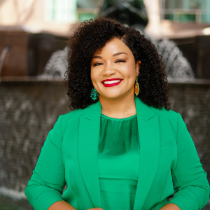 Woman wearing green suit smiling at camera.