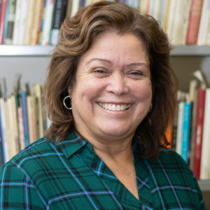 person smiling at camera in front of a bookcase