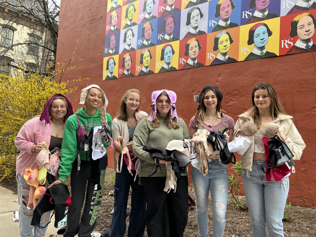 group of people standing outside holding a bunch of bras