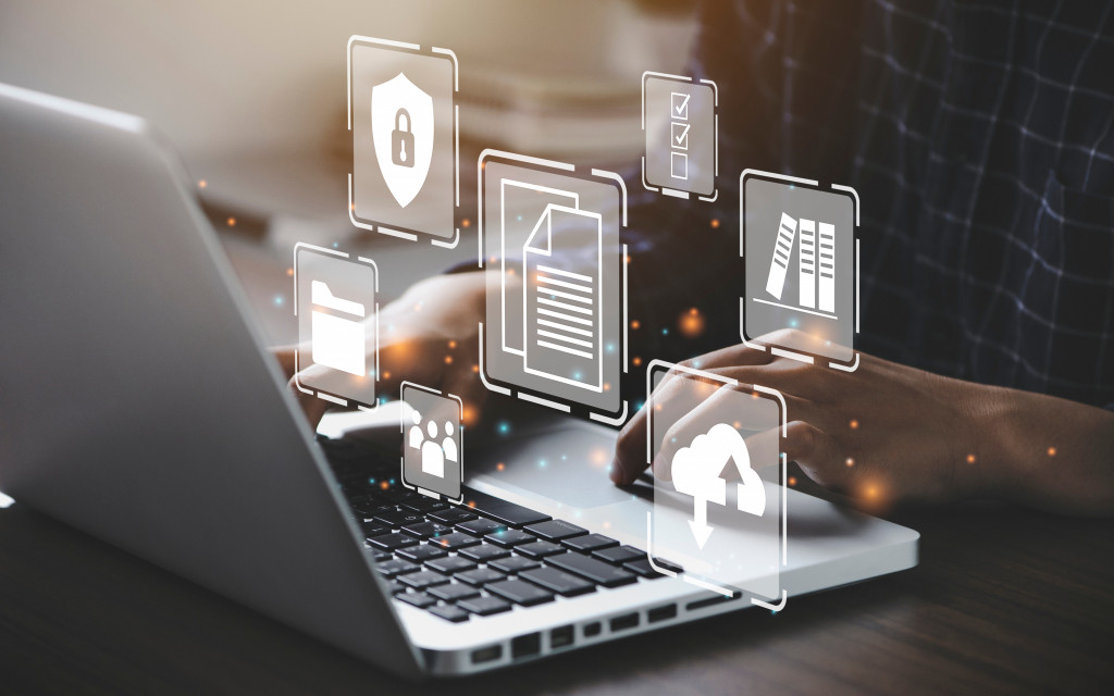 Person typing on laptop with digital business icons overlayed, representing skills learned in an MBA program such as document management, cloud computing, and team collaboration.