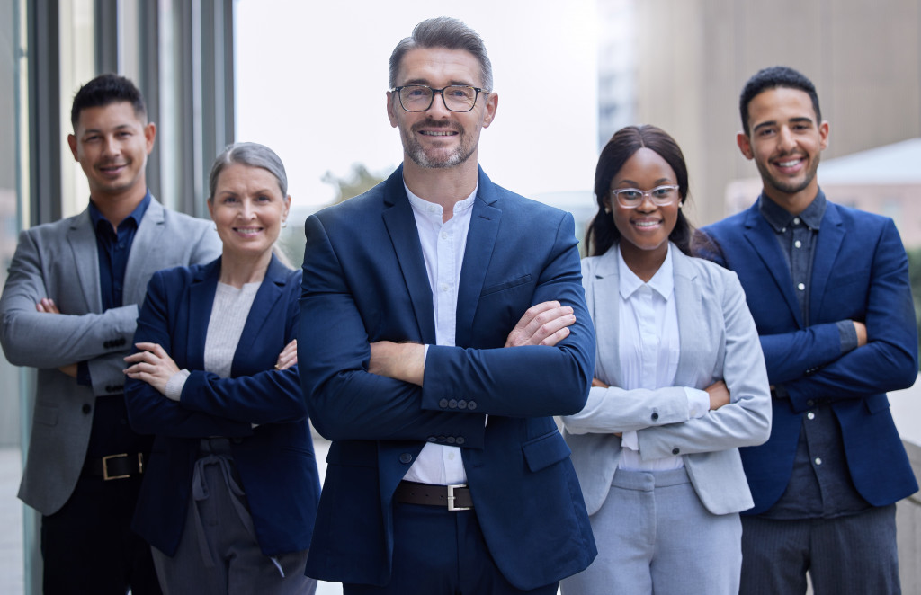 Group of diverse business professionals standing confidently with arms crossed, representing the varied backgrounds of students pursuing an MBA degree.