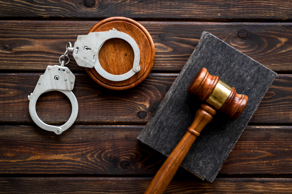 Wooden gavel, law book, and handcuffs on a dark table, representing careers in law enforcement and the legal system.