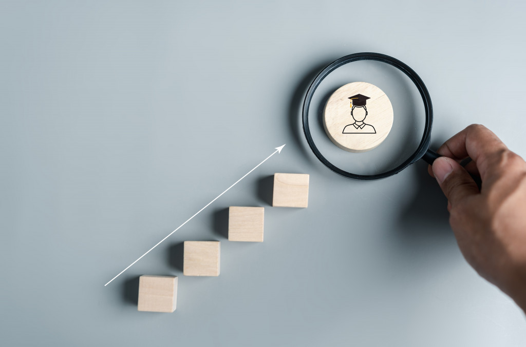 Steps to get a master's degree visualized with wooden blocks leading to a graduate icon, symbolizing academic achievement
