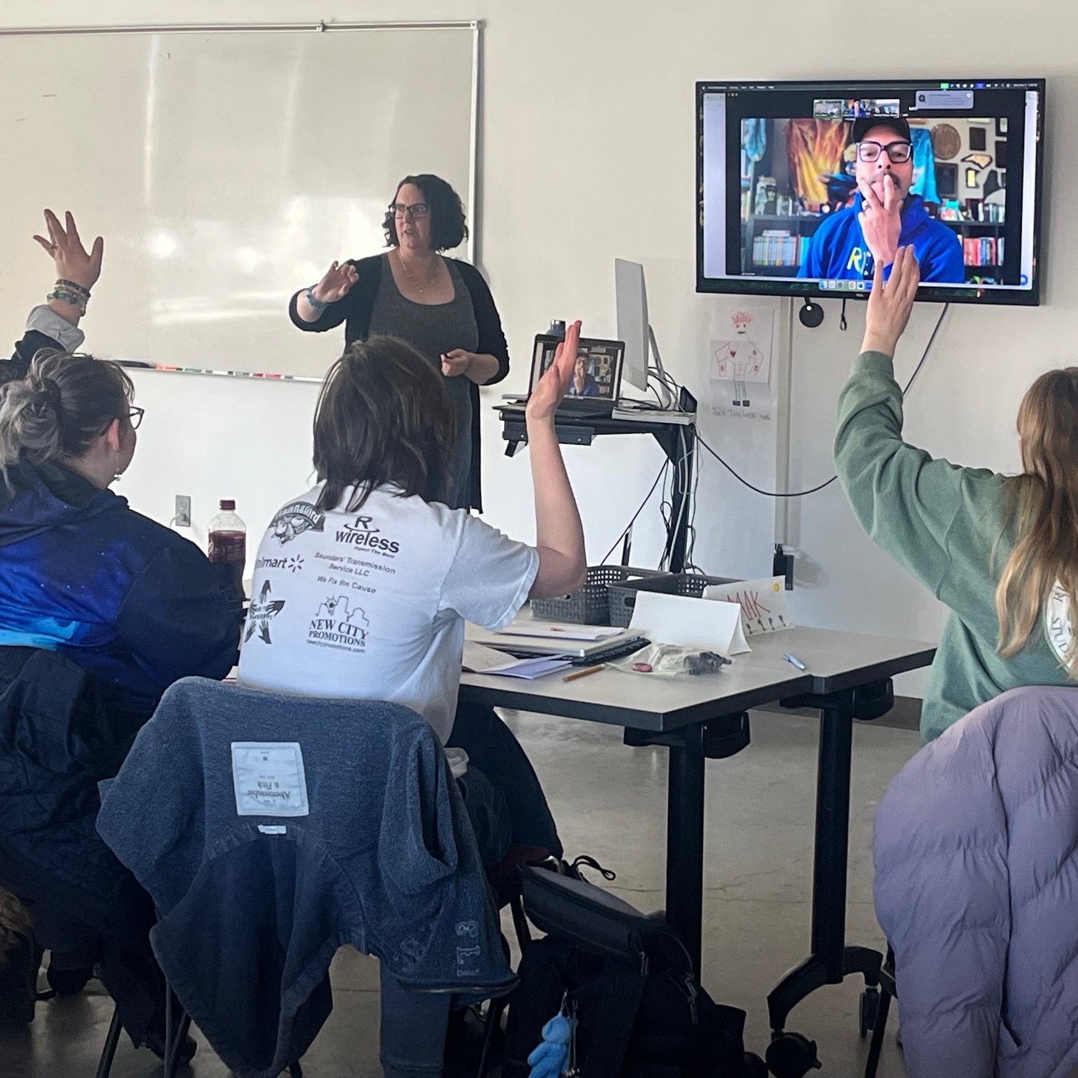 Students in a classroom with a virtual guest speaker on a screen