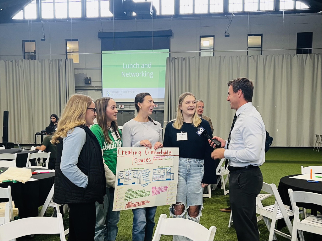 students talking to reporter and holding a poster they made