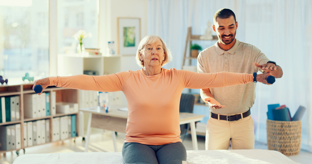 A physical therapist guides a patient through shoulder rehabilitation exercises using weights during a therapy session. 