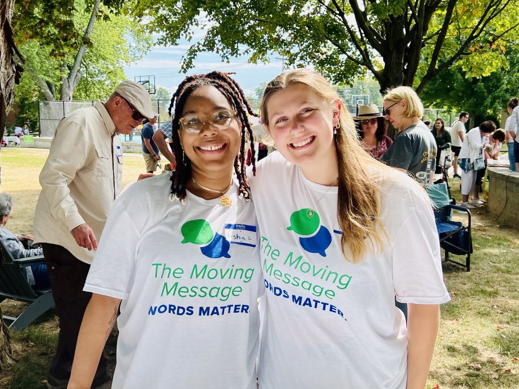 Two russell sage college students smile at the camera outside wearing Moving Message t-shirts.