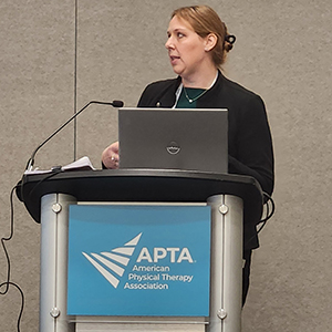 Person speaking at a podium with APTA logo and a laptop
