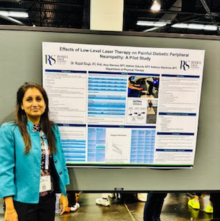 Woman standing beside an academic poster on low-level laser therapy