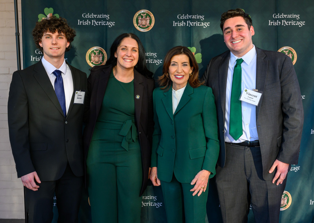 Four people standing together at an event with a backdrop reading "Celebrating Irish Heritage."