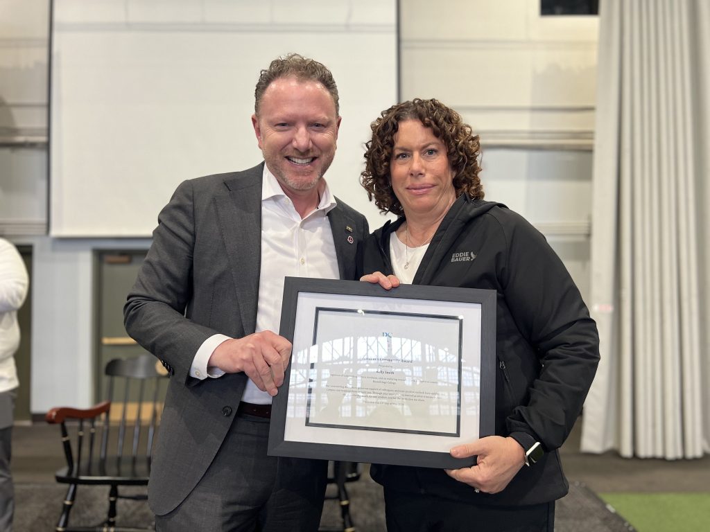 Two people holding a framed certificate indoors.