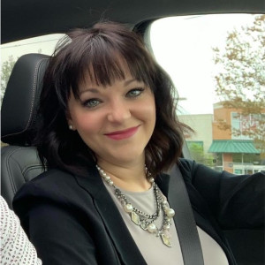 Woman in car wearing seatbelt dressed professionally and smiling at the camera