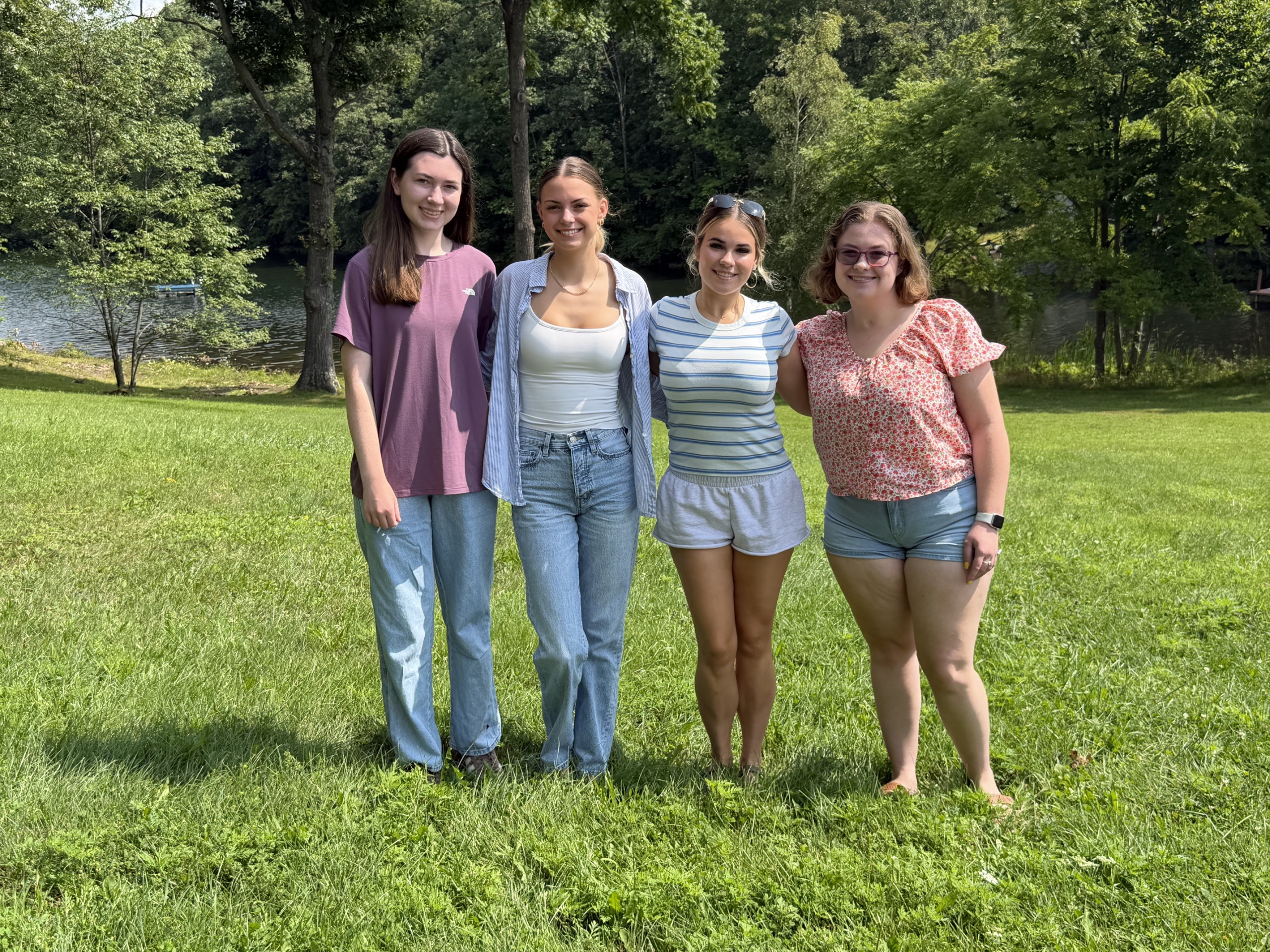 Four people standing outside in a line smiling at the camera