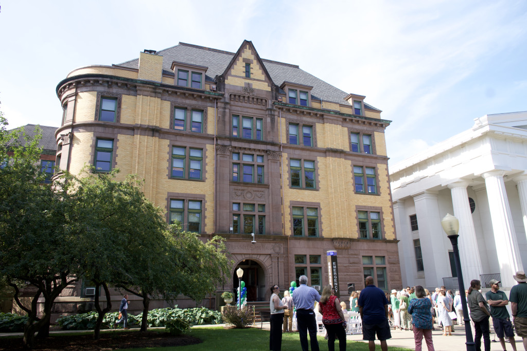Exterior photo of Sage Hall with crowd assembling for ceremony