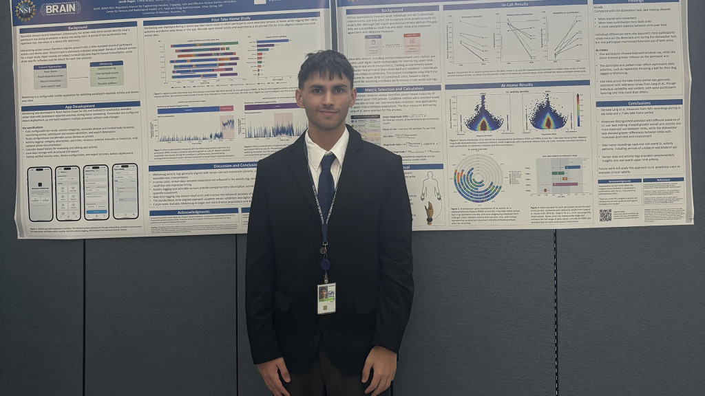 Person standing in front of two research posters about wearable activity monitoring and upper-limb movement.