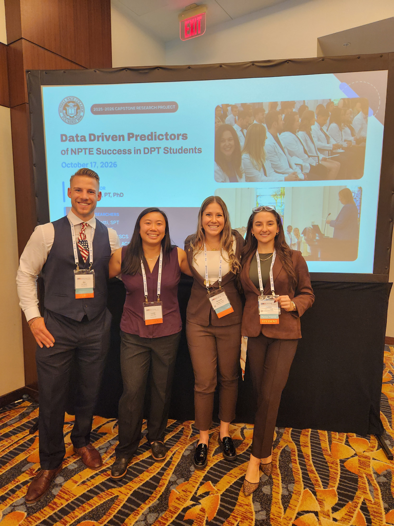 Four presenters pose in front of a screen displaying a capstone research presentation titled “Data Driven Predictors of NPTE Success in DPT Students.”