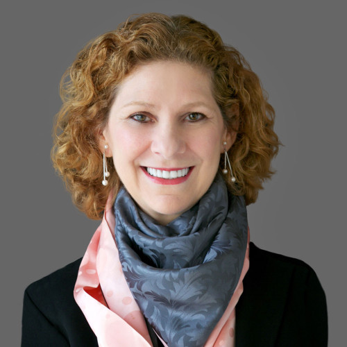 Woman wearing a scarf around her neck (fashion scarf) smiling at camera.