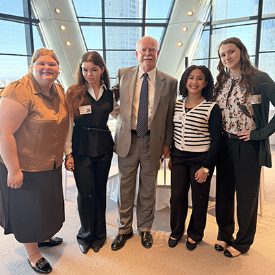 Five people pose together in a bright glass atrium.